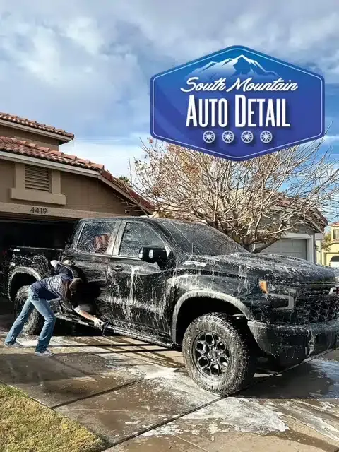 South Mountain Auto Detail technician pressure washing black truck at Chandler AZ driveway